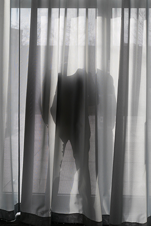 Mann hinter der Gardine